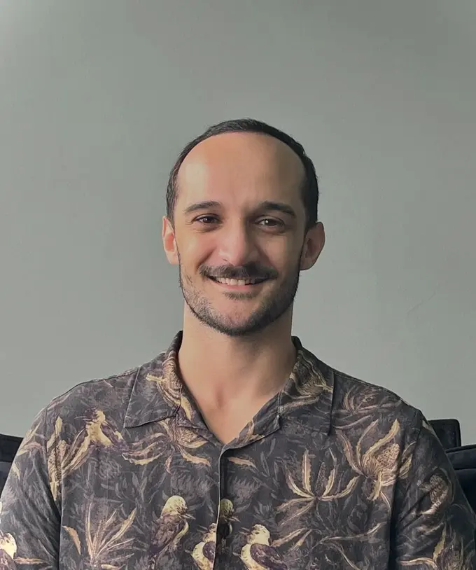 Gustavo Vieira Nery sorrindo, vestindo camisa estampada