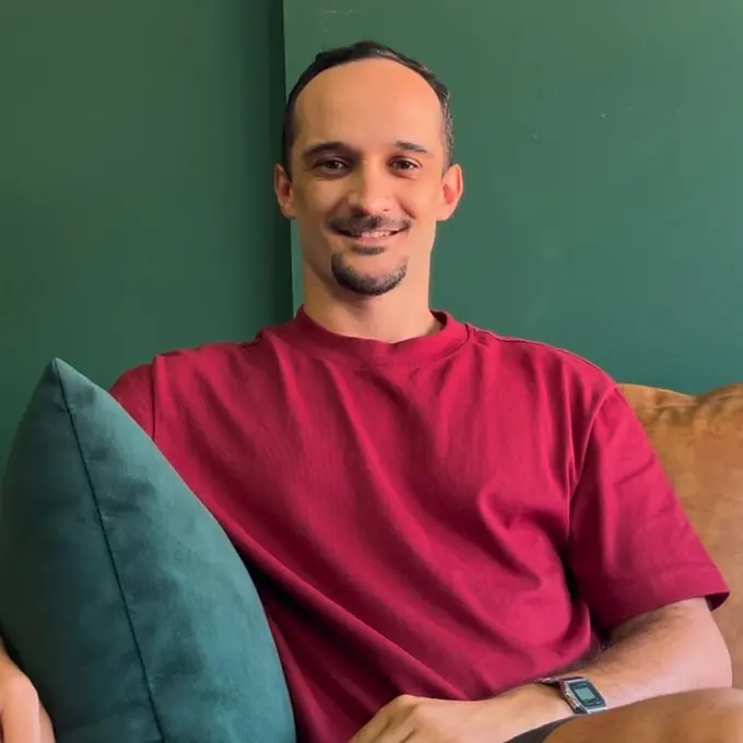 Gustavo Vieira Nery, psicólogo clínico, sorrindo, em ambiente acolhedor de fundo verde